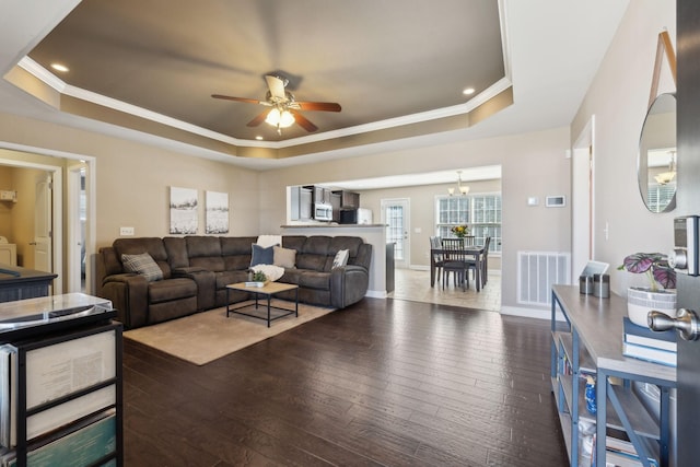 living room with visible vents, crown molding, a raised ceiling, and dark wood-type flooring