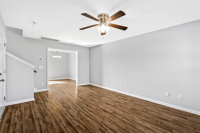 unfurnished living room featuring dark wood-type flooring, ceiling fan with notable chandelier, visible vents, and baseboards