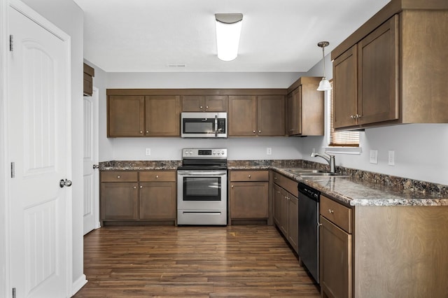 kitchen featuring hanging light fixtures, dark wood-style flooring, appliances with stainless steel finishes, and a sink