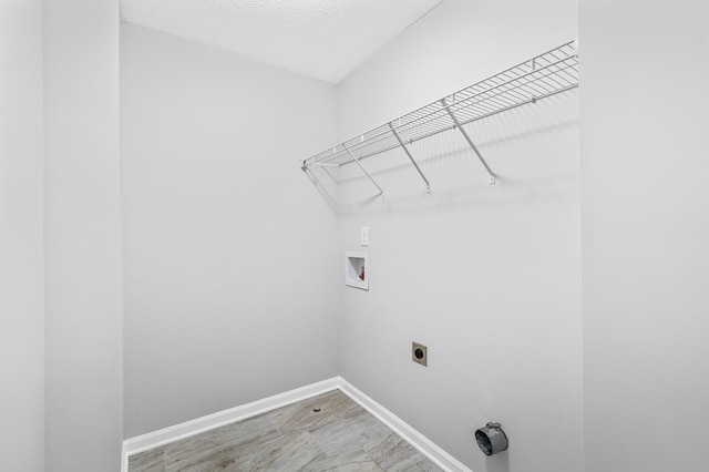 clothes washing area with baseboards, laundry area, electric dryer hookup, washer hookup, and a textured ceiling