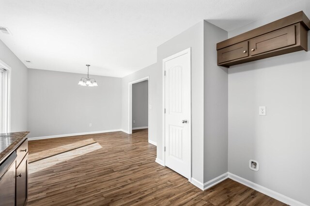 kitchen featuring stainless steel dishwasher, dark wood-type flooring, baseboards, and an inviting chandelier