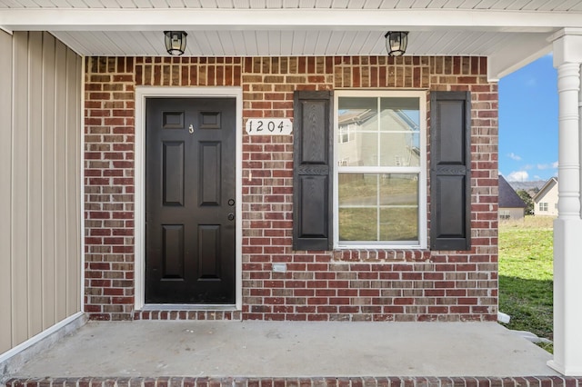 doorway to property with brick siding and covered porch