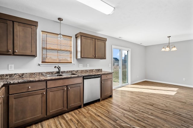 kitchen featuring a sink, decorative light fixtures, stainless steel dishwasher, and light wood-style flooring