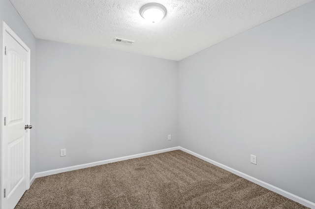 carpeted spare room featuring visible vents, baseboards, and a textured ceiling