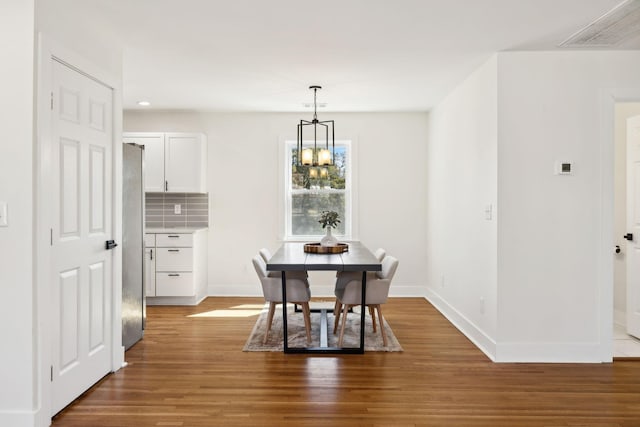 dining room featuring a chandelier, visible vents, baseboards, and wood finished floors