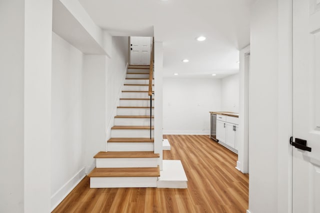 staircase featuring recessed lighting, baseboards, and wood finished floors