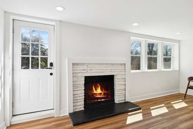 unfurnished living room featuring recessed lighting, a fireplace, baseboards, and wood finished floors