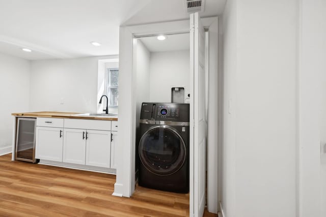 laundry room with visible vents, beverage cooler, light wood-style flooring, washer / clothes dryer, and a sink