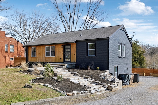 view of front of property with fence, brick siding, and a shingled roof