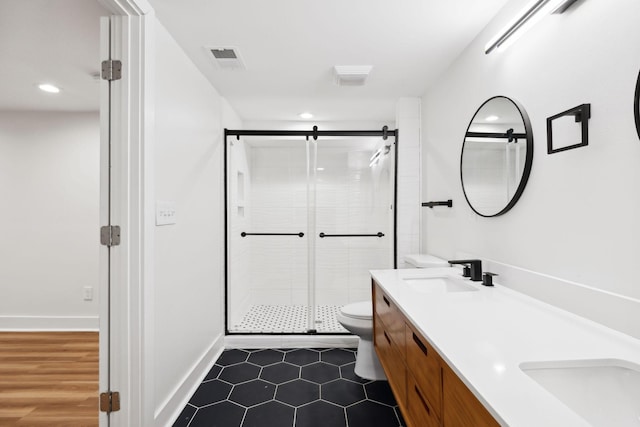 bathroom featuring visible vents, double vanity, a stall shower, a sink, and toilet