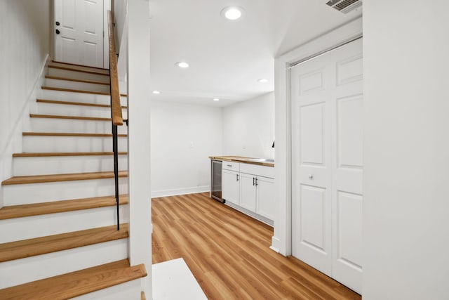 stairway with visible vents, beverage cooler, wood finished floors, recessed lighting, and baseboards