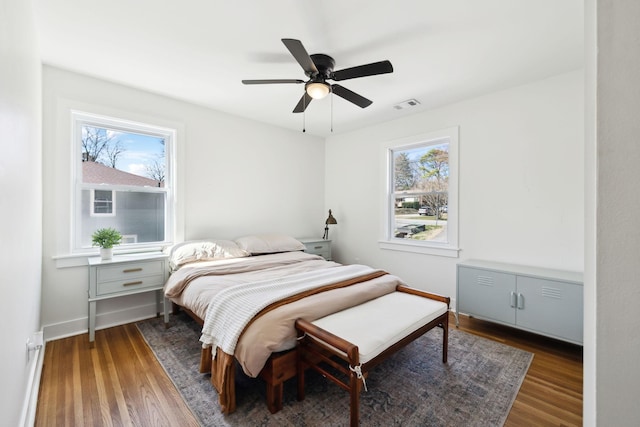 bedroom with ceiling fan, wood finished floors, visible vents, and baseboards