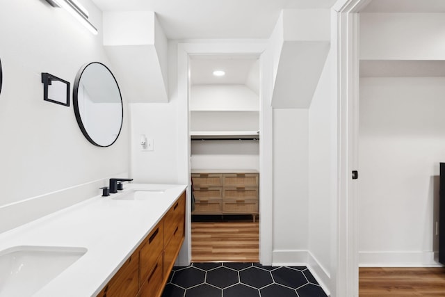 bathroom featuring double vanity, wood finished floors, baseboards, and a sink