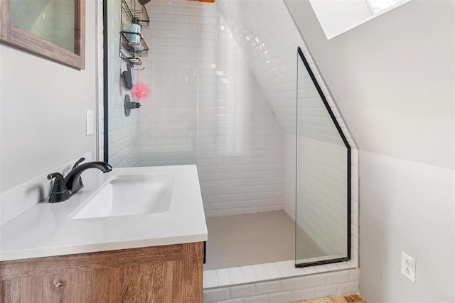 full bath with vanity, vaulted ceiling, and a tile shower