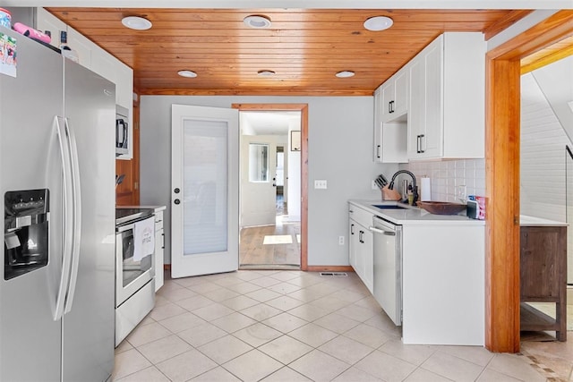 kitchen featuring a sink, appliances with stainless steel finishes, light countertops, light tile patterned floors, and decorative backsplash