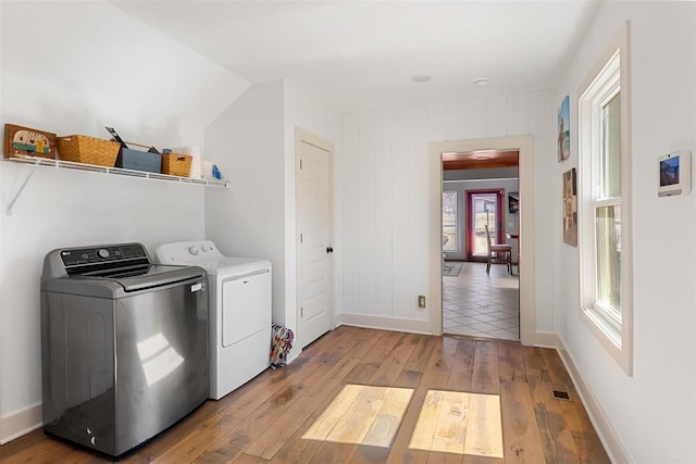 clothes washing area with laundry area, washer and dryer, baseboards, and hardwood / wood-style flooring