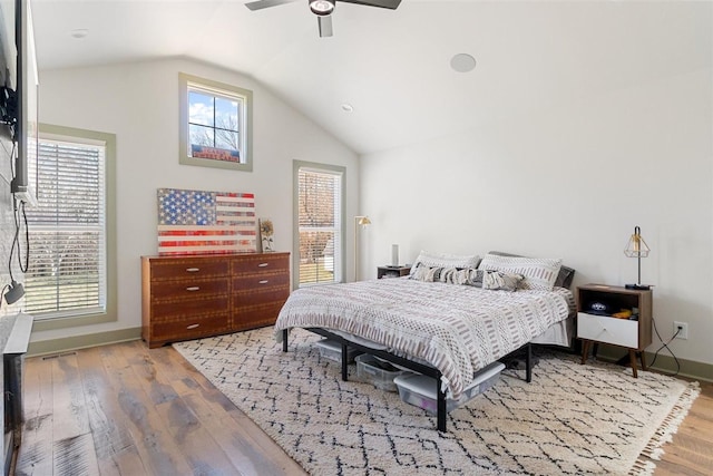 bedroom featuring a ceiling fan, wood finished floors, baseboards, visible vents, and lofted ceiling