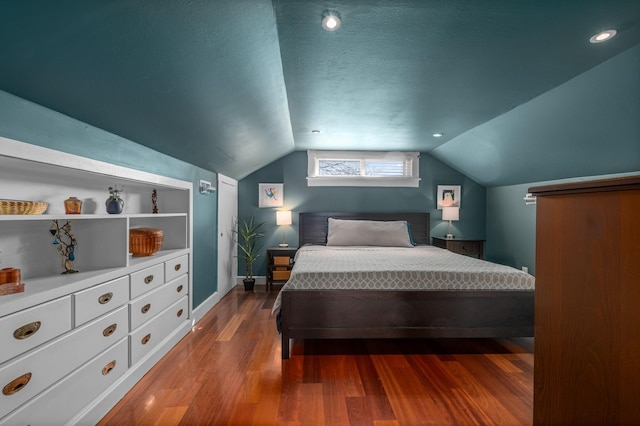 bedroom with baseboards, a textured ceiling, lofted ceiling, and wood finished floors