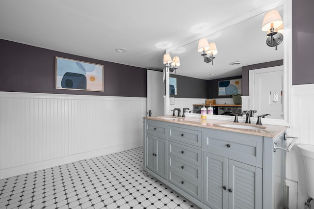 full bathroom with a sink, double vanity, tile patterned floors, and wainscoting