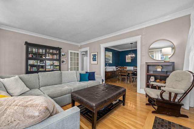 living room featuring light wood-style floors, a chandelier, and crown molding