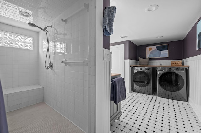 interior space featuring washing machine and dryer, visible vents, a tile shower, and wainscoting