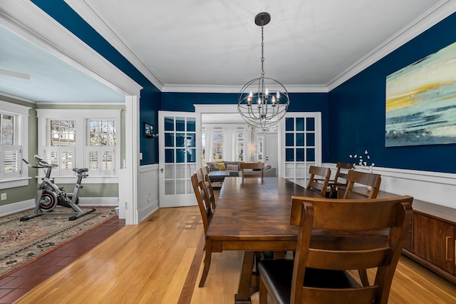 dining area featuring light wood-style floors, a chandelier, and ornamental molding