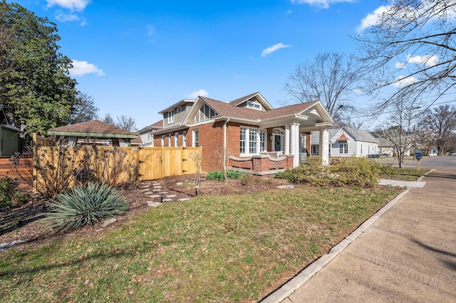 view of front facade featuring brick siding, a front lawn, a gate, and fence