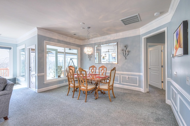 carpeted dining area with visible vents, a decorative wall, a wainscoted wall, and ornamental molding