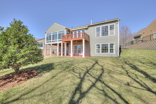 rear view of house with a wooden deck, a sunroom, a lawn, and a patio area