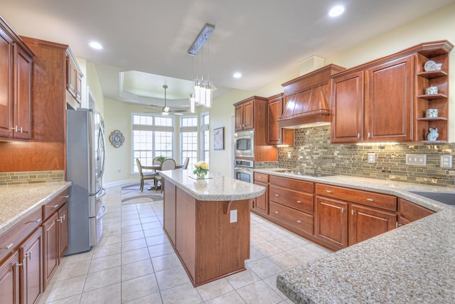 kitchen with a tray ceiling, a center island, light tile patterned floors, and stainless steel appliances