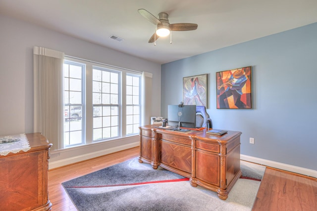 home office with visible vents, baseboards, wood finished floors, and a ceiling fan