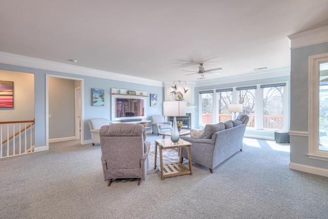 living area with baseboards, carpet, a glass covered fireplace, and crown molding