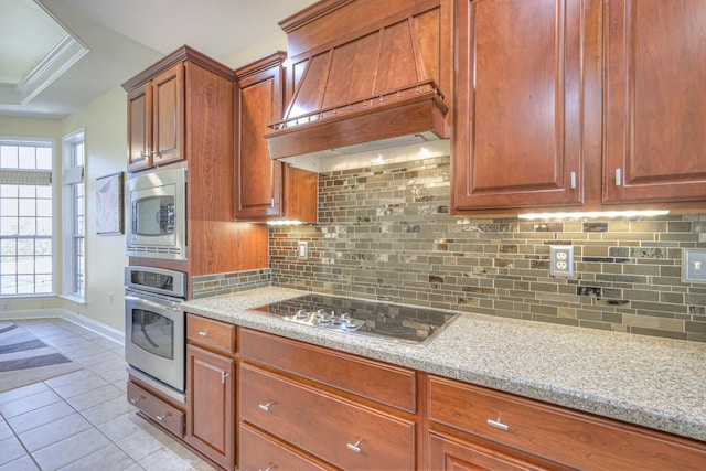 kitchen featuring a raised ceiling, stainless steel appliances, light tile patterned flooring, decorative backsplash, and baseboards