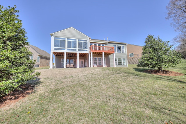 back of house featuring a lawn, a deck, and a sunroom