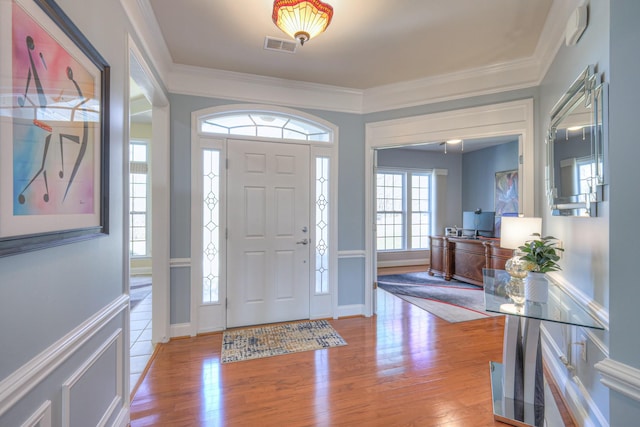 entryway featuring visible vents, ornamental molding, baseboards, and wood finished floors