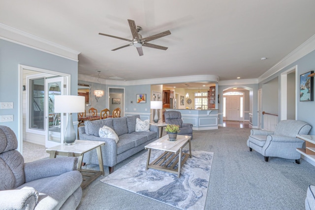 living area with crown molding, carpet, arched walkways, and ceiling fan