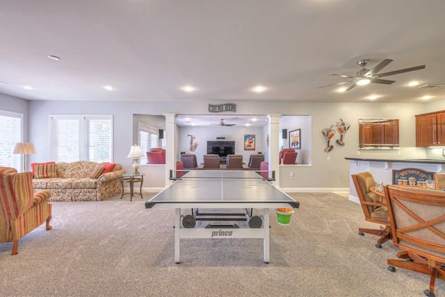 recreation room featuring a wealth of natural light, a ceiling fan, ornate columns, and carpet floors