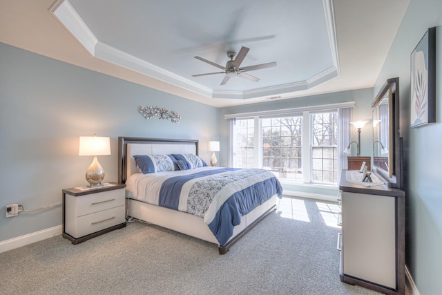 carpeted bedroom with visible vents, crown molding, baseboards, a tray ceiling, and a ceiling fan