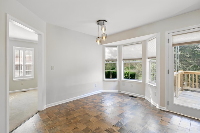 unfurnished room with stone finish floor, a notable chandelier, baseboards, and visible vents