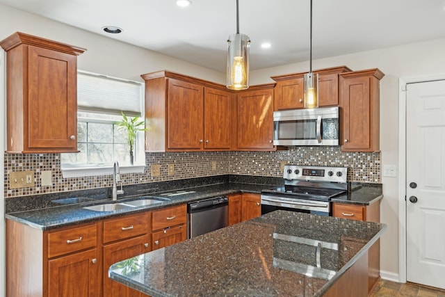 kitchen with backsplash, pendant lighting, brown cabinets, stainless steel appliances, and a sink