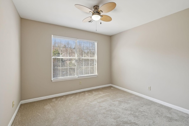 carpeted empty room with a ceiling fan and baseboards