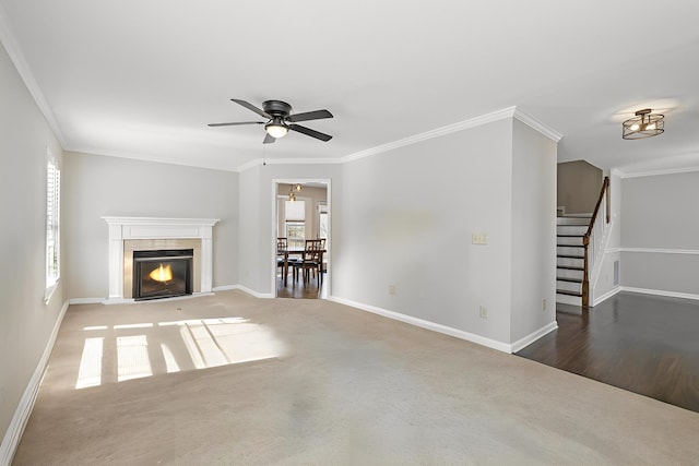 unfurnished living room featuring stairway, a fireplace with flush hearth, baseboards, and ornamental molding