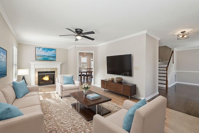 living room with stairway, crown molding, baseboards, and wood finished floors