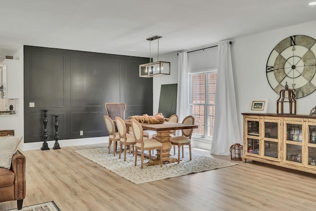 dining area with light wood-style floors and a decorative wall