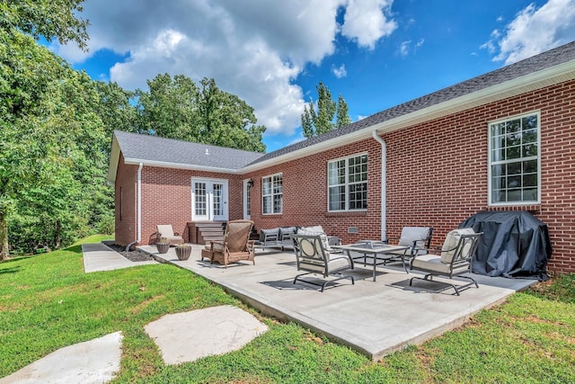 back of property with an outdoor hangout area, a lawn, brick siding, and a patio area