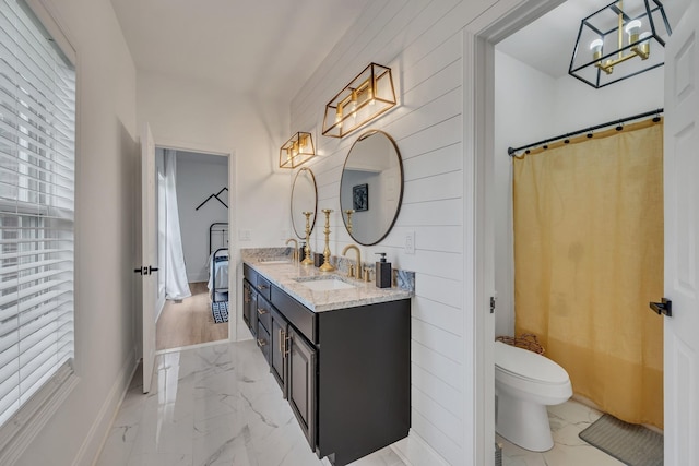 full bathroom featuring double vanity, marble finish floor, toilet, and a sink