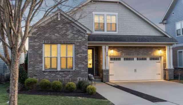 view of front of property with brick siding, driveway, and a garage