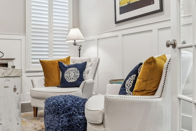 living area featuring wood finished floors, wainscoting, and a decorative wall