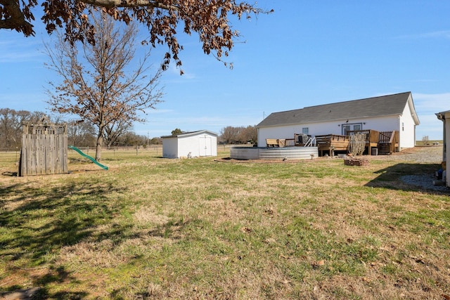 view of yard with a storage unit, a deck, an outdoor structure, and a playground