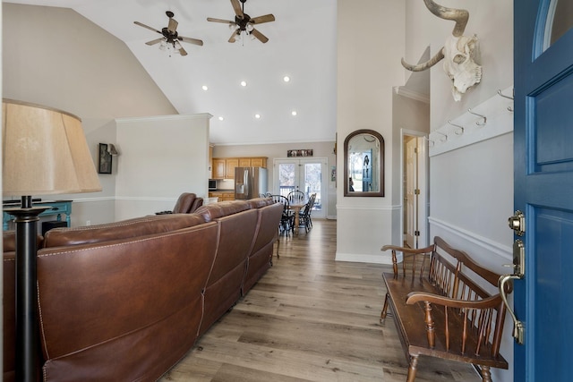 living room featuring baseboards, light wood-style floors, high vaulted ceiling, and crown molding